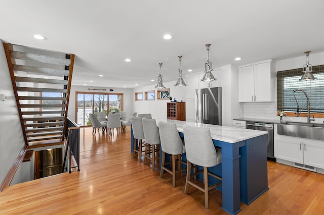 kitchen with stainless steel appliances, a sink, a kitchen island, white cabinets, and recessed lighting