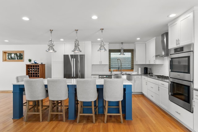 kitchen with appliances with stainless steel finishes, wall chimney exhaust hood, a sink, tasteful backsplash, and recessed lighting