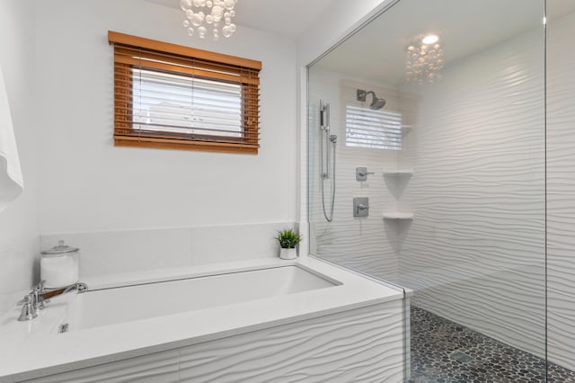 full bathroom with a garden tub, a walk in shower, and a chandelier