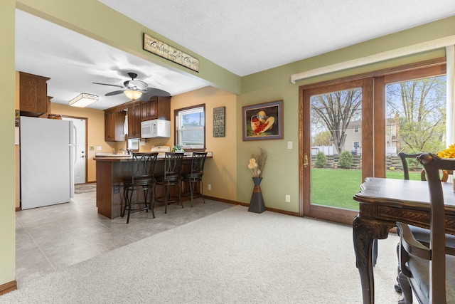 10851 Olive St NW, Coon Rapids, MN 55448 - kitchen with white appliances, a kitchen breakfast bar, a peninsula, light carpet, and ceiling fan