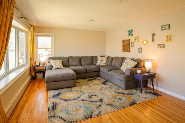 living area featuring baseboard heating, baseboards, and wood finished floors