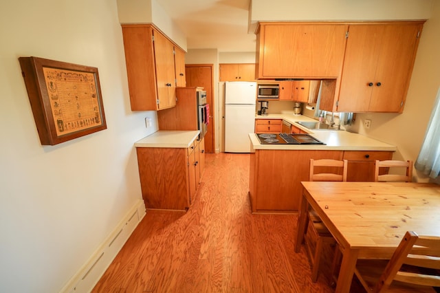 kitchen with light wood-type flooring, a sink, light countertops, a peninsula, and stainless steel appliances