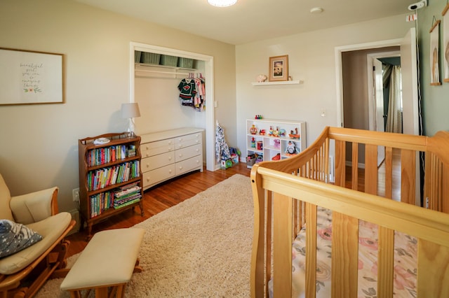 bedroom featuring a closet, wood finished floors, and a nursery area