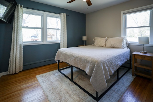 bedroom featuring baseboards, ceiling fan, a baseboard heating unit, and hardwood / wood-style flooring