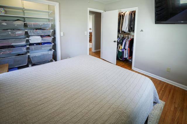 bedroom with baseboards, a closet, wood finished floors, and a spacious closet