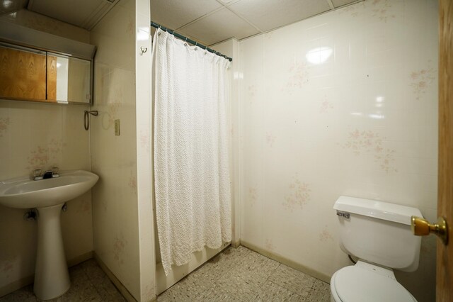 full bath featuring a shower with curtain, a sink, tile patterned floors, toilet, and a drop ceiling