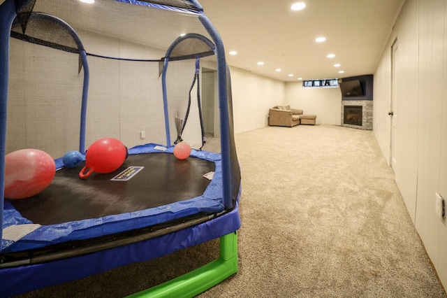exercise room with carpet floors, a fireplace, and recessed lighting