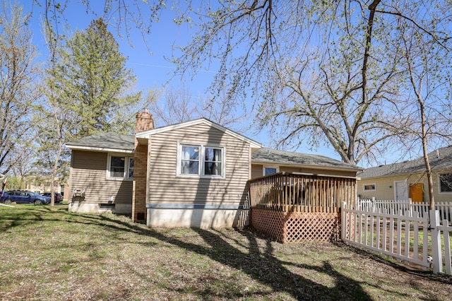 rear view of property with a yard, fence, a chimney, and a wooden deck