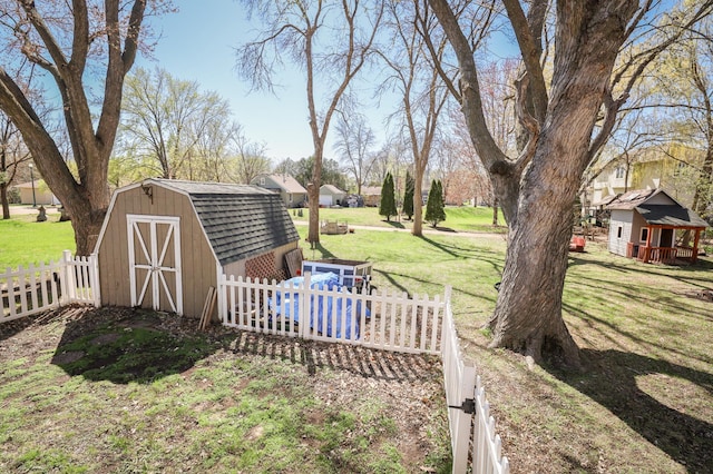 view of yard with fence, an outdoor structure, and a storage unit