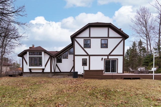 rear view of property with a wooden deck, a chimney, a yard, and stucco siding