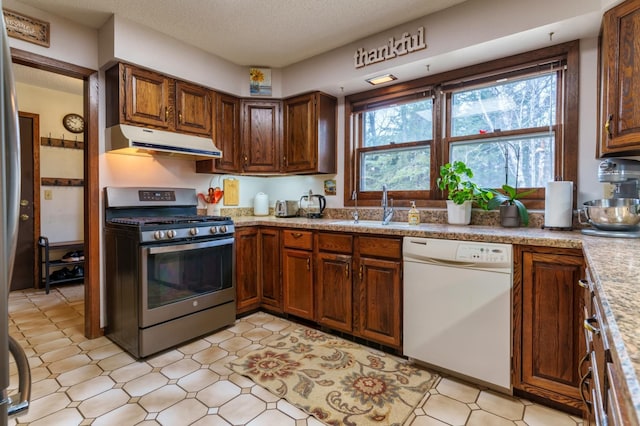 kitchen featuring stainless steel gas range oven, range hood, light countertops, a sink, and dishwasher