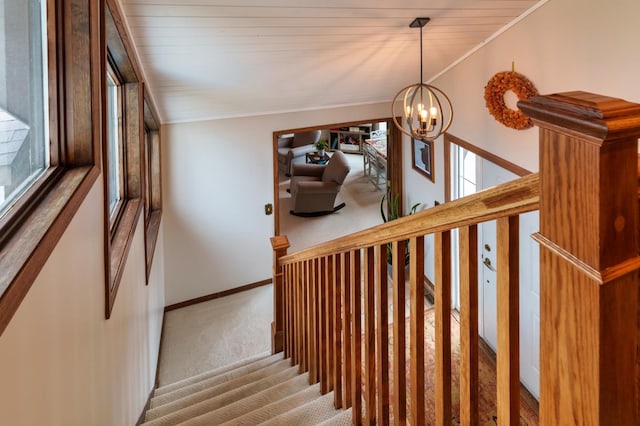 stairway featuring crown molding, baseboards, a notable chandelier, and carpet