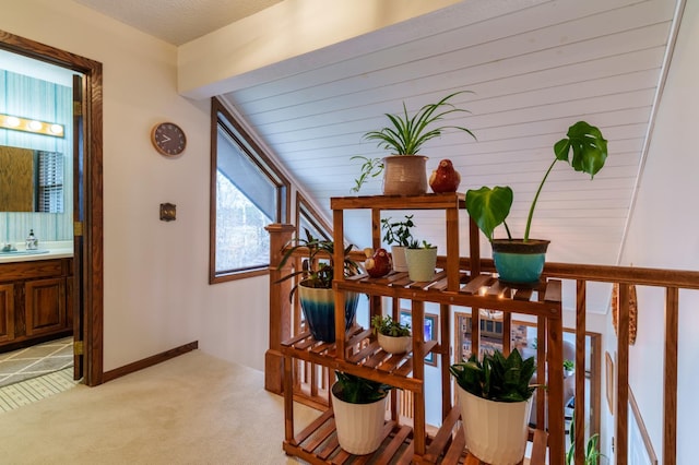 hallway featuring a sink and light colored carpet