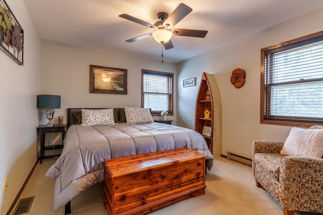 bedroom featuring ceiling fan, a textured ceiling, visible vents, light colored carpet, and a baseboard heating unit