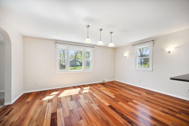 19797 612th Ave, Litchfield, MN 55355 - spare room with arched walkways, healthy amount of natural light, wood finished floors, and baseboards