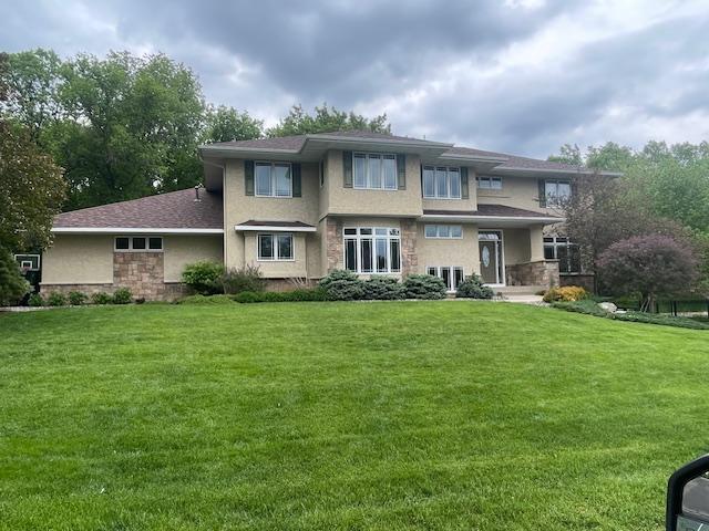 rear view of property featuring a lawn, stucco siding, and stone siding