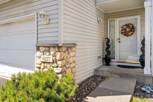 doorway to property with a garage and stone siding