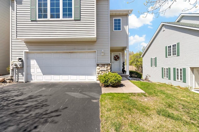 view of front facade featuring an attached garage, stone siding, asphalt driveway, and a front lawn