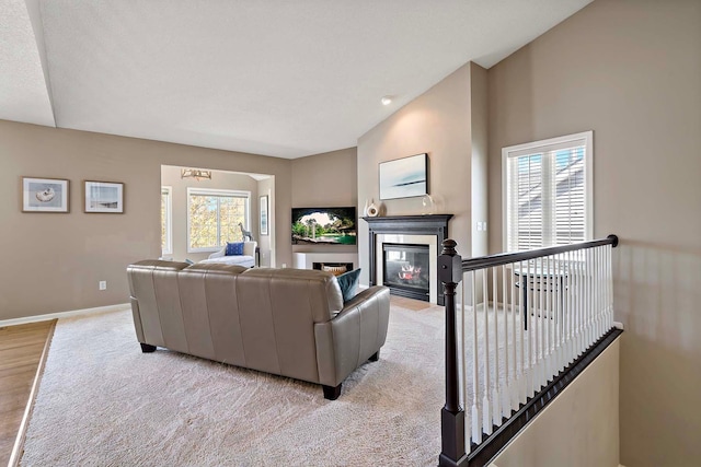 living area featuring baseboards, a fireplace with flush hearth, and light wood finished floors