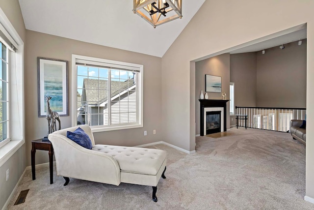 living area with carpet flooring, baseboards, a chandelier, high vaulted ceiling, and a fireplace