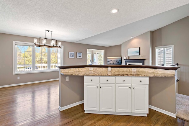 kitchen with dark wood finished floors, baseboards, a textured ceiling, white cabinetry, and lofted ceiling