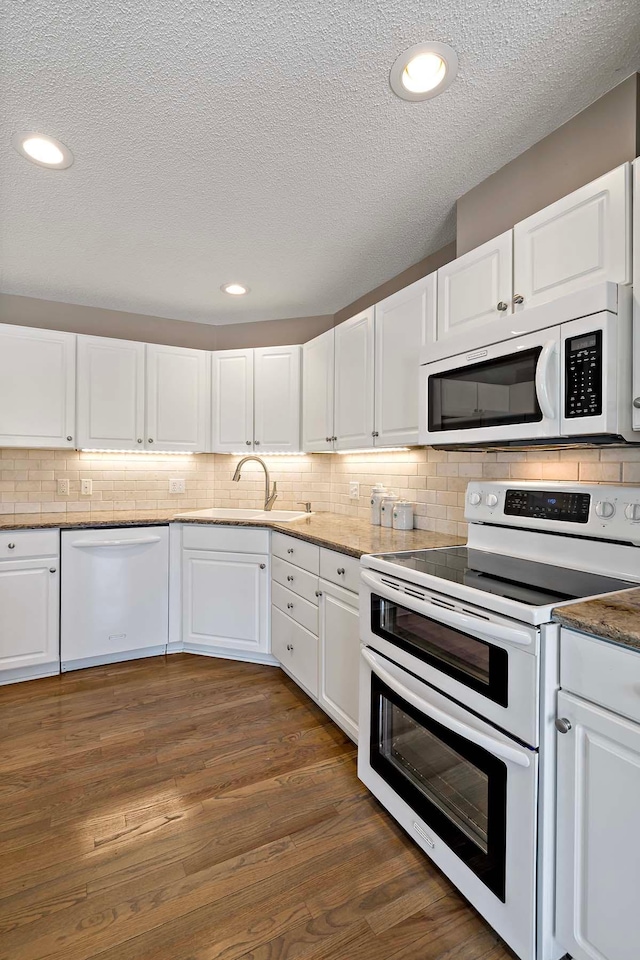 kitchen featuring white appliances, a sink, a textured ceiling, white cabinets, and backsplash