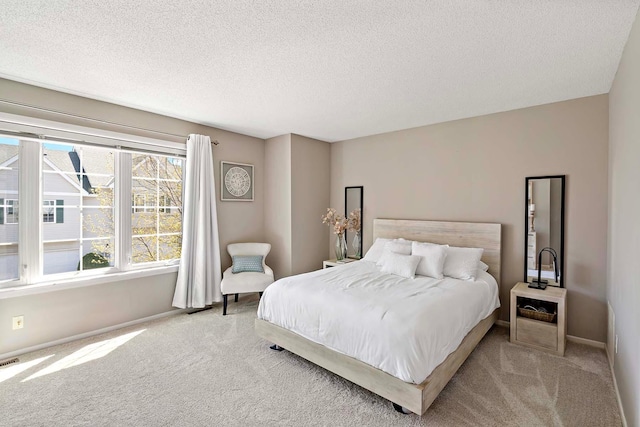 bedroom featuring light colored carpet, baseboards, and a textured ceiling