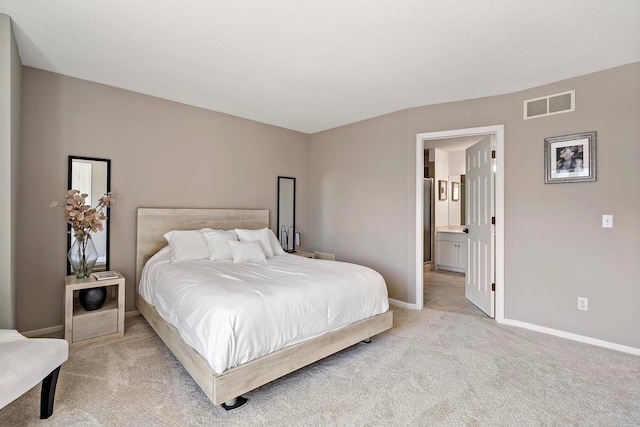 bedroom featuring light colored carpet, baseboards, and connected bathroom