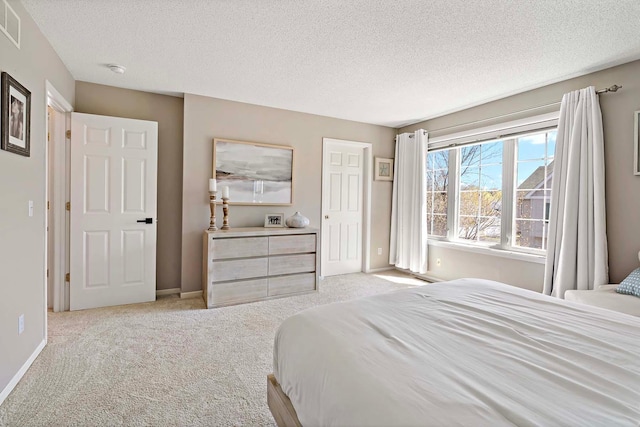 bedroom featuring light carpet, a textured ceiling, and baseboards
