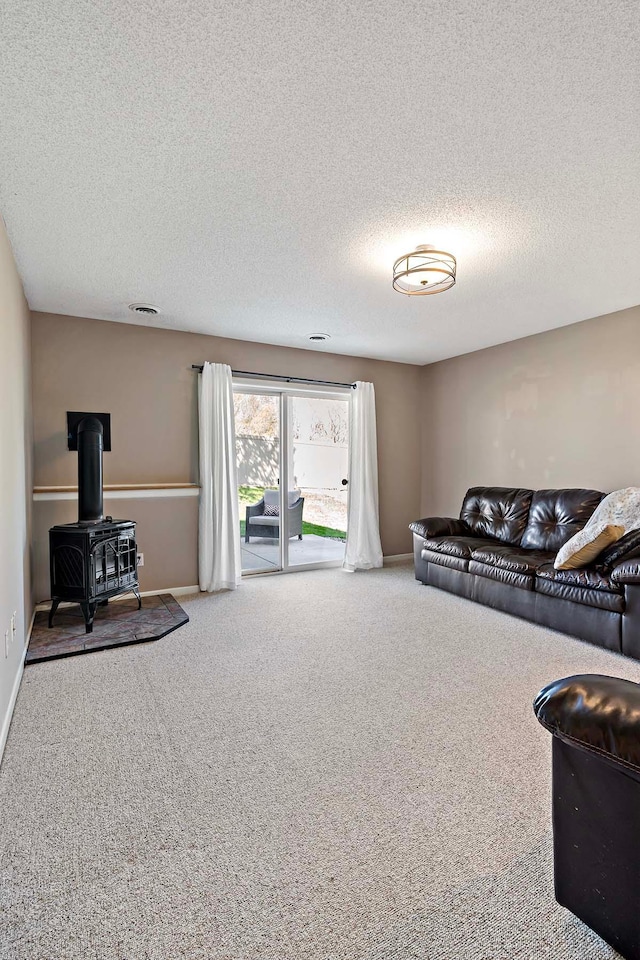 living room with carpet floors, a textured ceiling, a wood stove, and baseboards