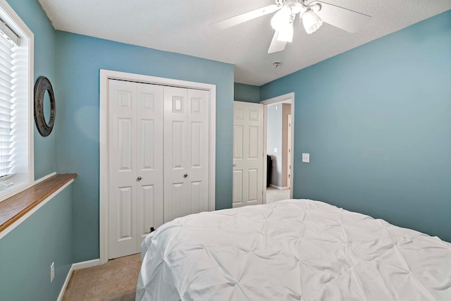 carpeted bedroom with a closet, baseboards, and a ceiling fan