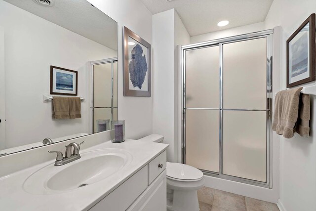 full bathroom featuring a stall shower, toilet, vanity, and tile patterned flooring