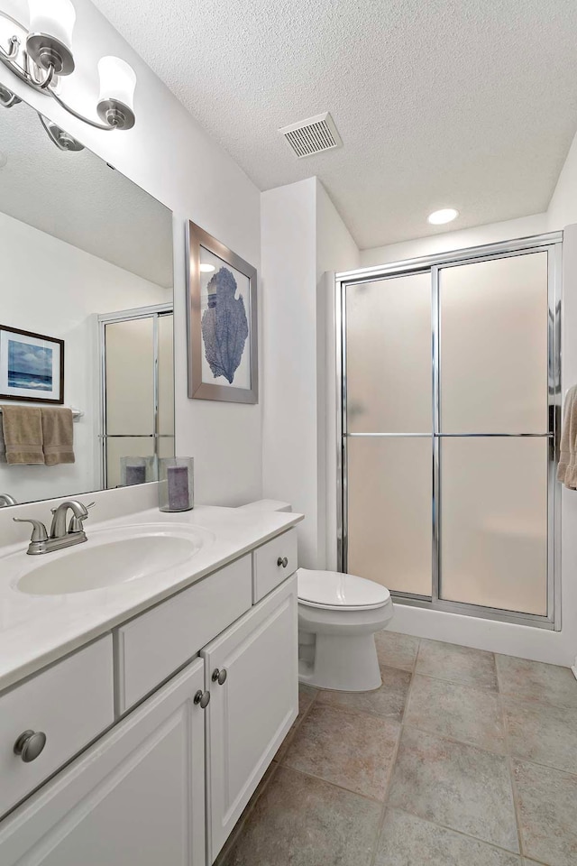 full bath with a stall shower, toilet, a textured ceiling, and vanity