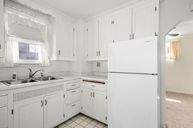 kitchen featuring a sink, freestanding refrigerator, light countertops, and white cabinets