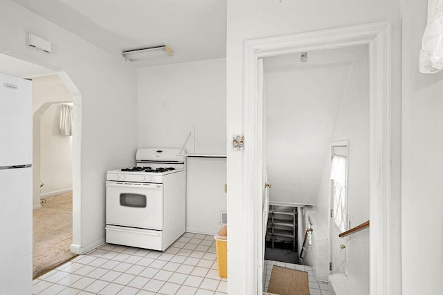 kitchen with white appliances, arched walkways, and light tile patterned floors