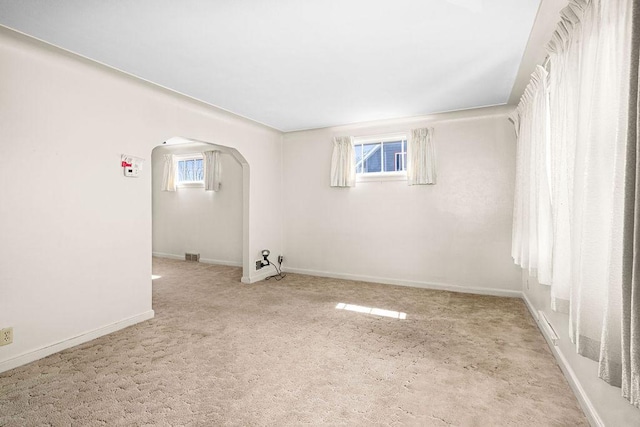 interior space featuring carpet flooring, arched walkways, baseboards, and visible vents