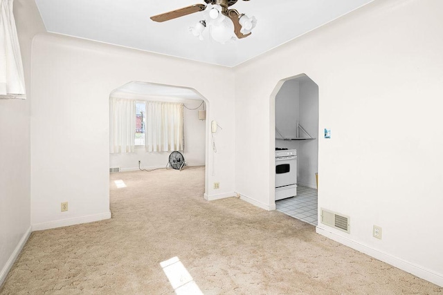 unfurnished room featuring baseboards, ceiling fan, visible vents, arched walkways, and carpet floors