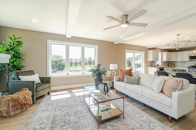 living area with wood finished floors, beam ceiling, baseboards, recessed lighting, and ceiling fan with notable chandelier