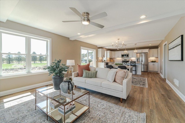 living area with baseboards, ceiling fan with notable chandelier, recessed lighting, and wood finished floors