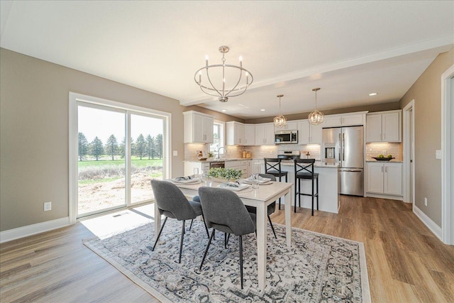 dining area with an inviting chandelier, light wood-style flooring, baseboards, and recessed lighting