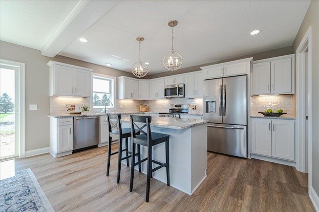 kitchen with backsplash, stainless steel appliances, light wood-style flooring, and a chandelier