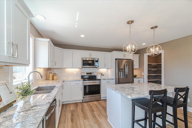 kitchen featuring appliances with stainless steel finishes, backsplash, light wood-style flooring, and white cabinetry