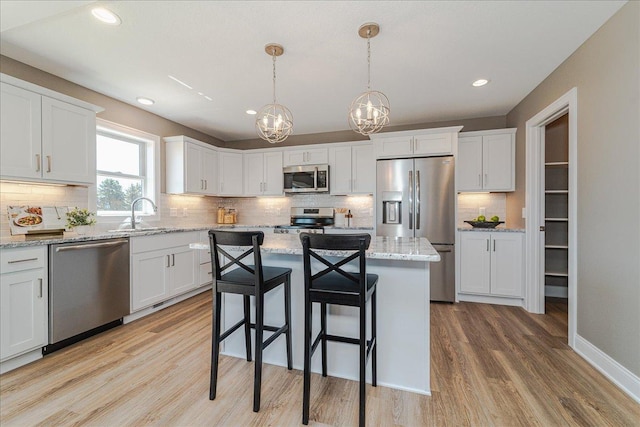 kitchen featuring white cabinetry, a sink, light wood finished floors, a notable chandelier, and stainless steel appliances