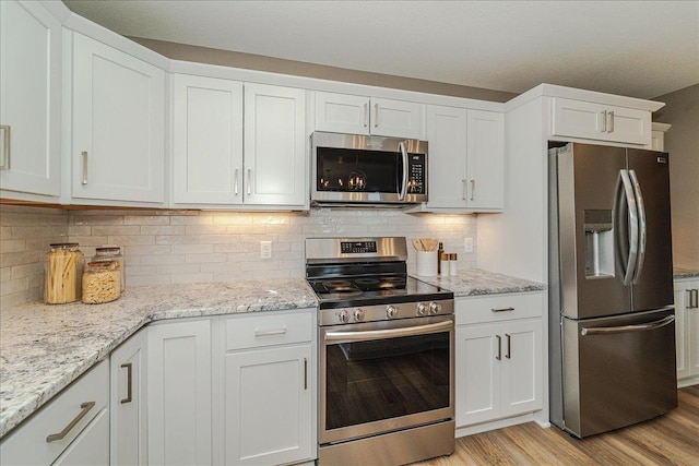 kitchen with white cabinets, appliances with stainless steel finishes, and light wood-style floors