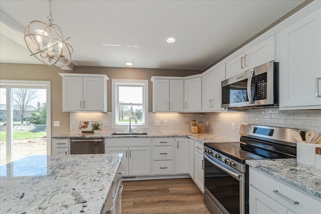 kitchen with white cabinets, dark wood-style flooring, appliances with stainless steel finishes, a sink, and tasteful backsplash