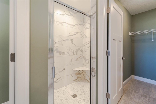 bathroom with baseboards, a shower stall, and a walk in closet