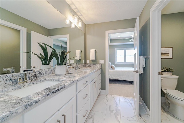 ensuite bathroom with baseboards, a sink, marble finish floor, and toilet