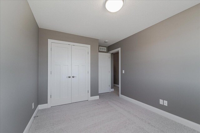 unfurnished bedroom with baseboards, light carpet, a closet, and visible vents