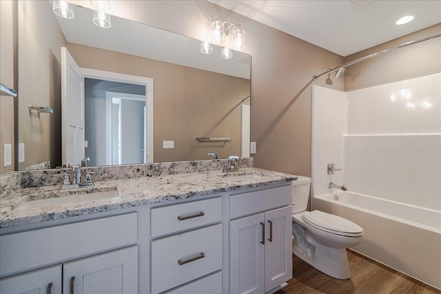 full bathroom featuring double vanity, toilet, a sink, and wood finished floors