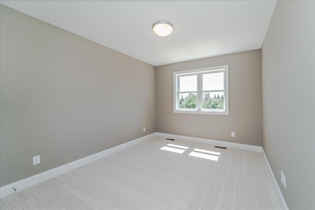 carpeted spare room with baseboards and visible vents